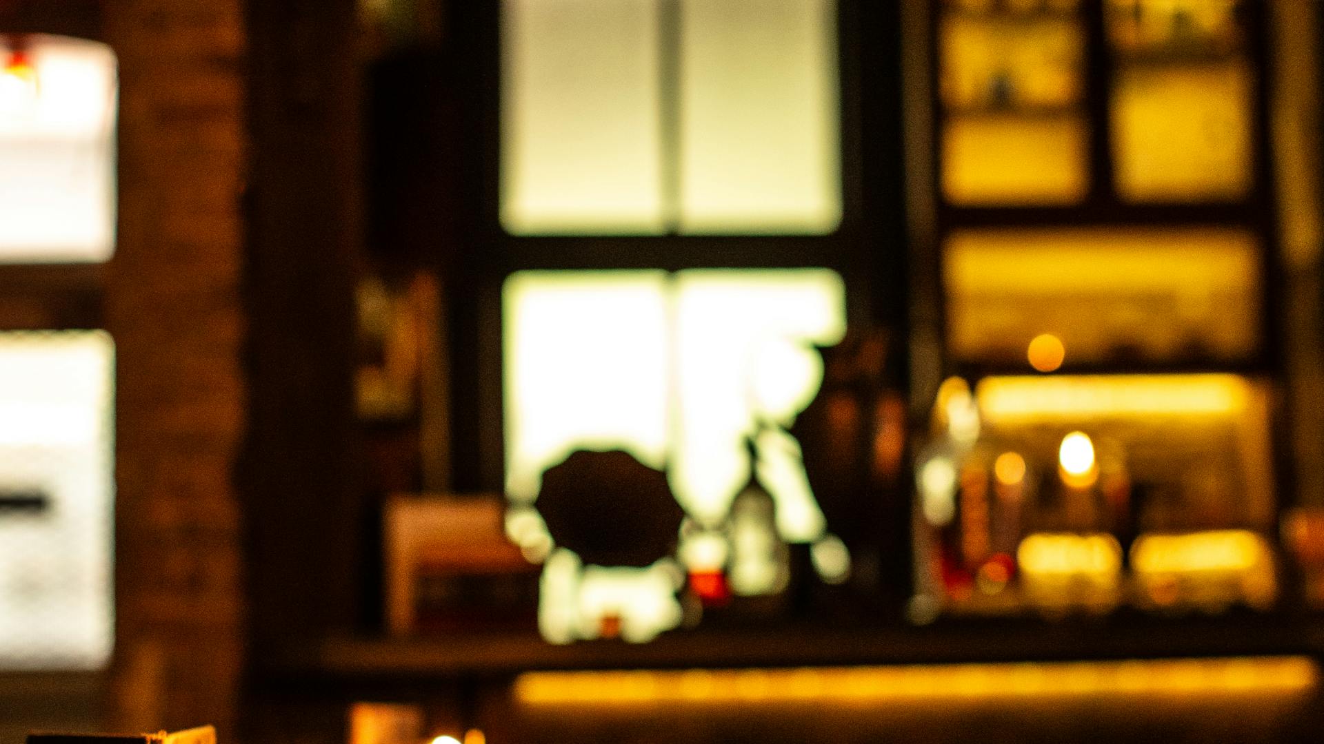 Candlelit wine bar interior with warm golden lighting and wooden shelves